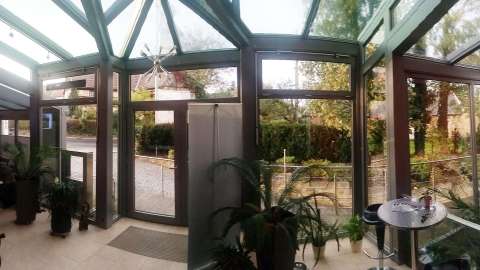 Innenansicht eines Eingangsbereichs mit Vollverglasung und vielen Topfpflanzen